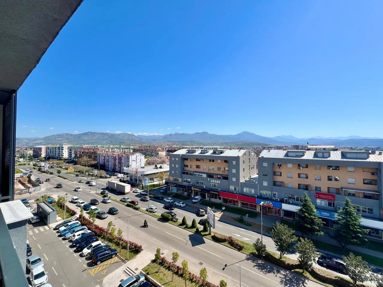 Pogled sa terase na gradski bulevar i planine u daljini.