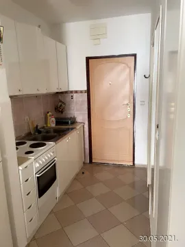 Small white kitchen with a stove and sink next to the entrance door. - image 3