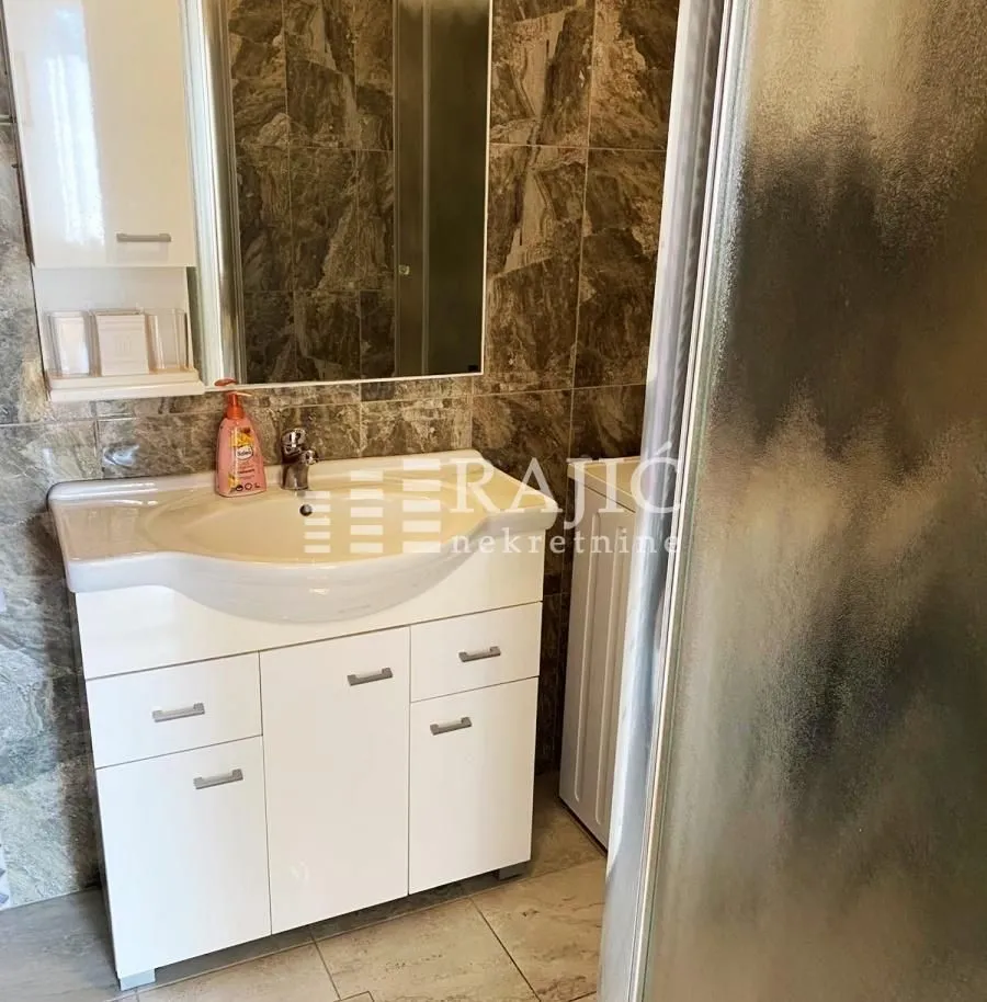 Small bathroom with a sink, vanity cabinet, and shower cabin.