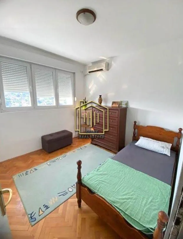Furnished bedroom with a wooden bed, chest of drawers, and a window.
