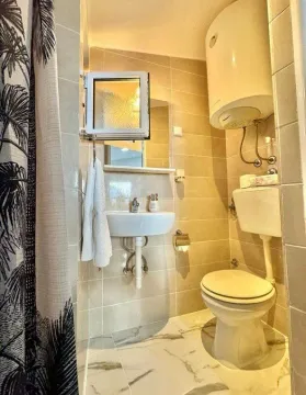 Smaller bathroom with a sink, toilet, and water heater. - image 2