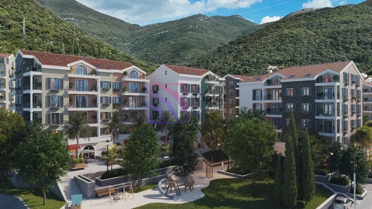 Pogled na stambeni kompleks sa uređenim dvorištem i igralištem.