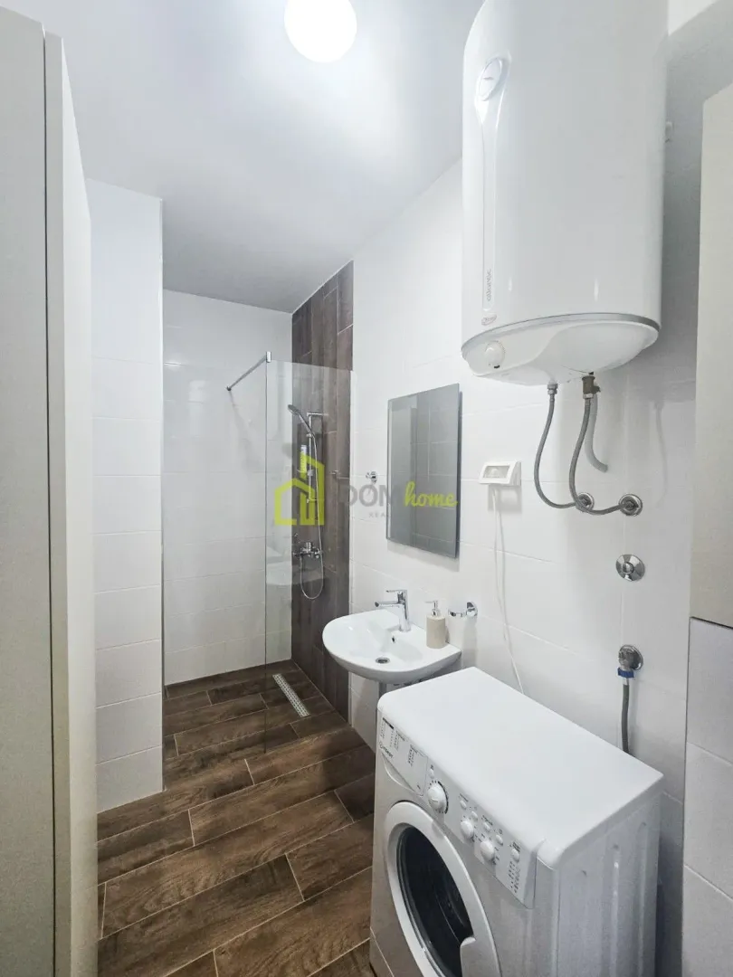 Bathroom with a shower cabin, washbasin, washing machine, and water heater.