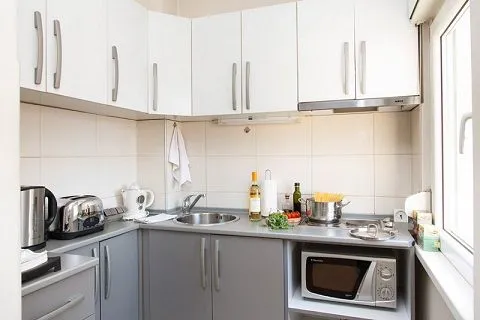 Manja kuhinja sa belim visećim elementima i sivim donjim elementima.