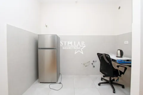 Small kitchen with a refrigerator and a desk with a chair. - image 3