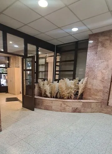 Building entrance hall with glass doors and decorative plants.