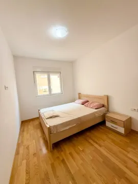 Svjetla spavaća soba sa drvenim krevetom i noćnim stolićem. - image 5