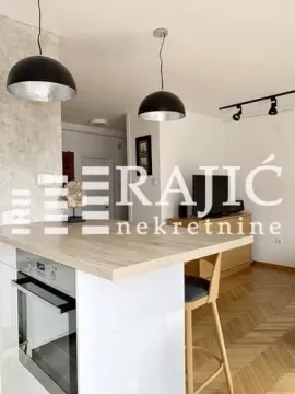 Modern kitchen with a breakfast bar and built-in oven opening into the living area. - image 4