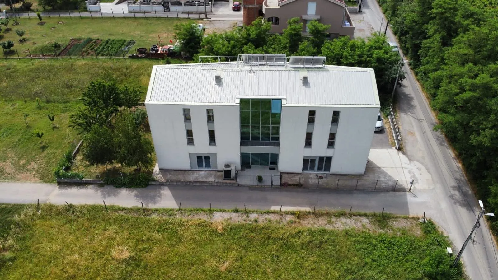 Aerial view of the exterior of a modern white building with a yard.