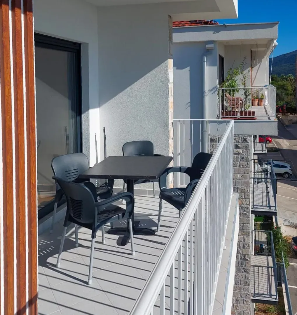 Natkriveni balkon sa garniturom za sedenje i stolom.