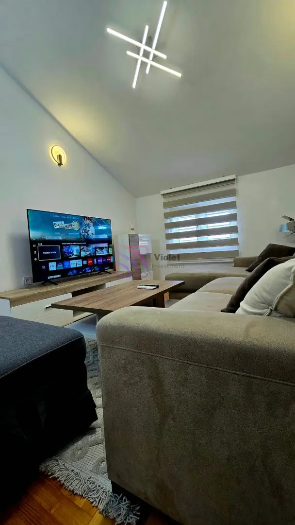 Living room with a sectional sofa, television, and modern lighting.