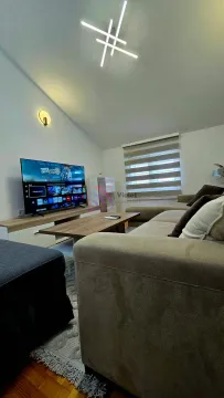 Living room with a sectional sofa, television, and modern lighting. - image 11