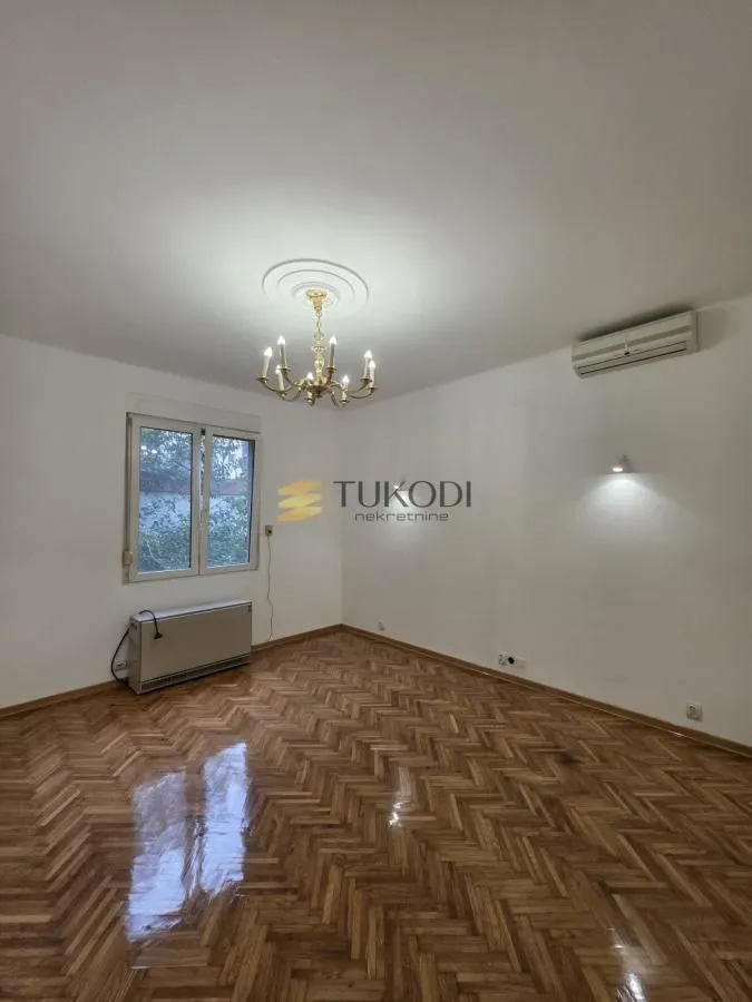 Empty room with parquet flooring and a chandelier on the ceiling.