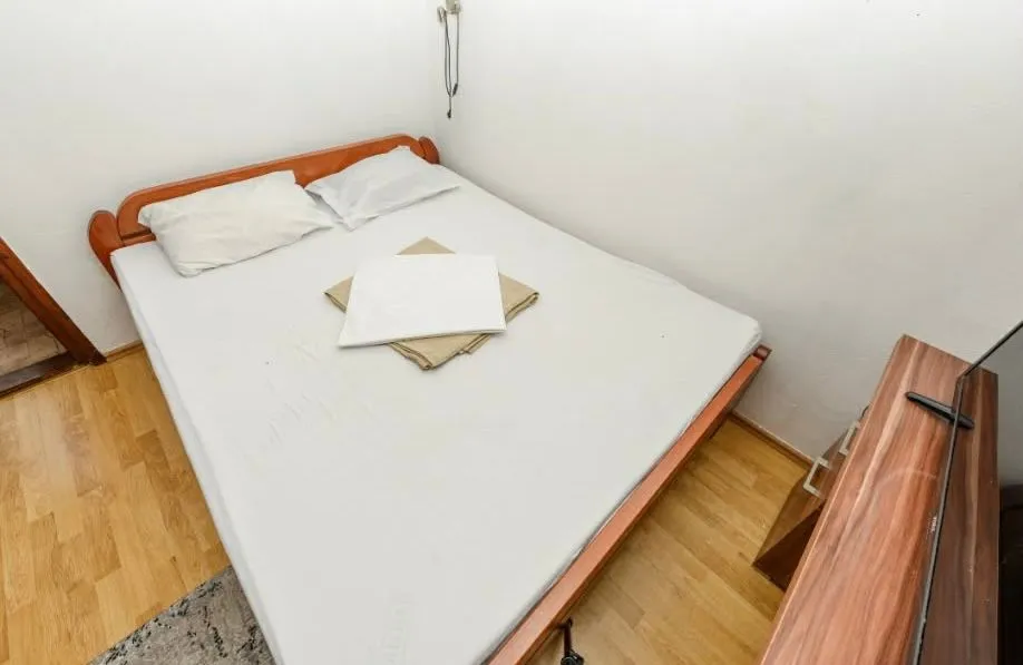 Small bedroom with a double bed and wooden flooring.