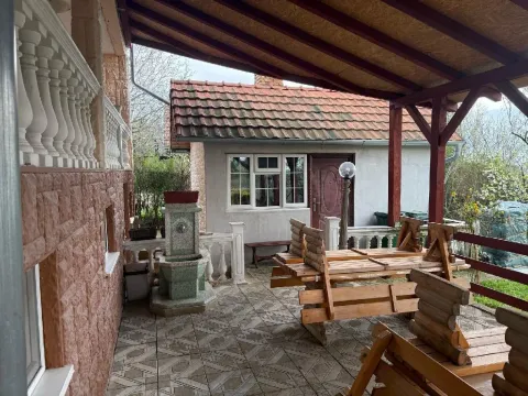 Natkrivena terasa sa drvenim stolovima i klupama ispred kuće. - image 10