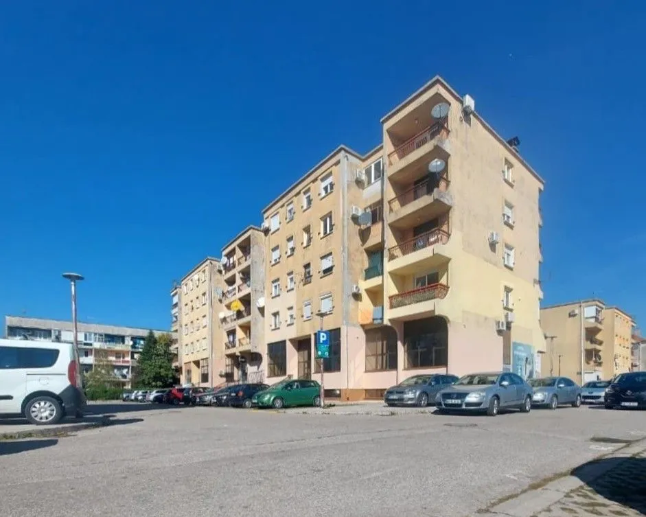 Exterior view of an apartment building with parking in front.