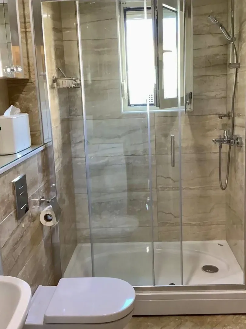 Moderno opremljeno kupatilo sa tuš kabinom i sanitarijama.