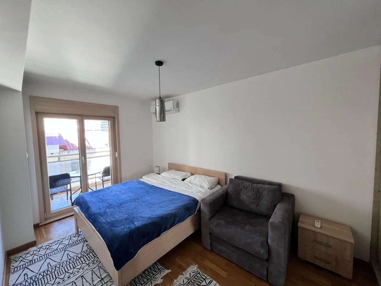 Furnished bedroom with a double bed, armchair, and balcony access.