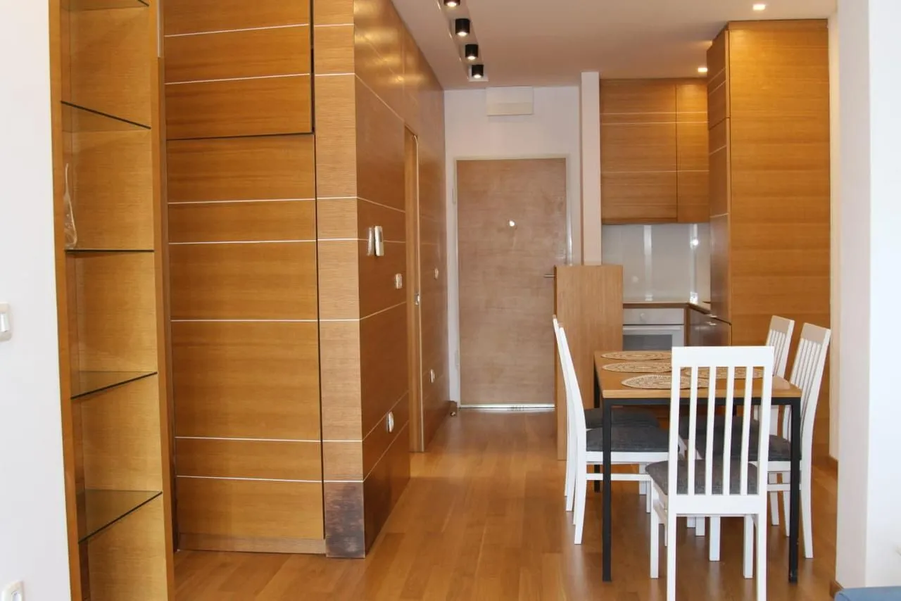 Dining area with wooden elements and a built-in kitchen in the background.