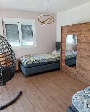 Furnished bedroom with a bed, wardrobe, and a hanging chair. - image 9