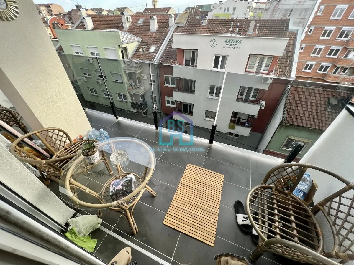 Namešten balkon sa garniturom za sedenje i pogledom na grad.