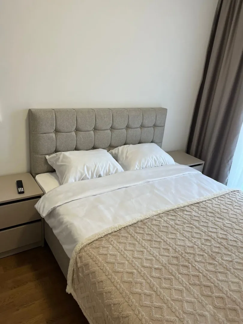 Namještena spavaća soba sa bračnim krevetom i noćnim stočićima.