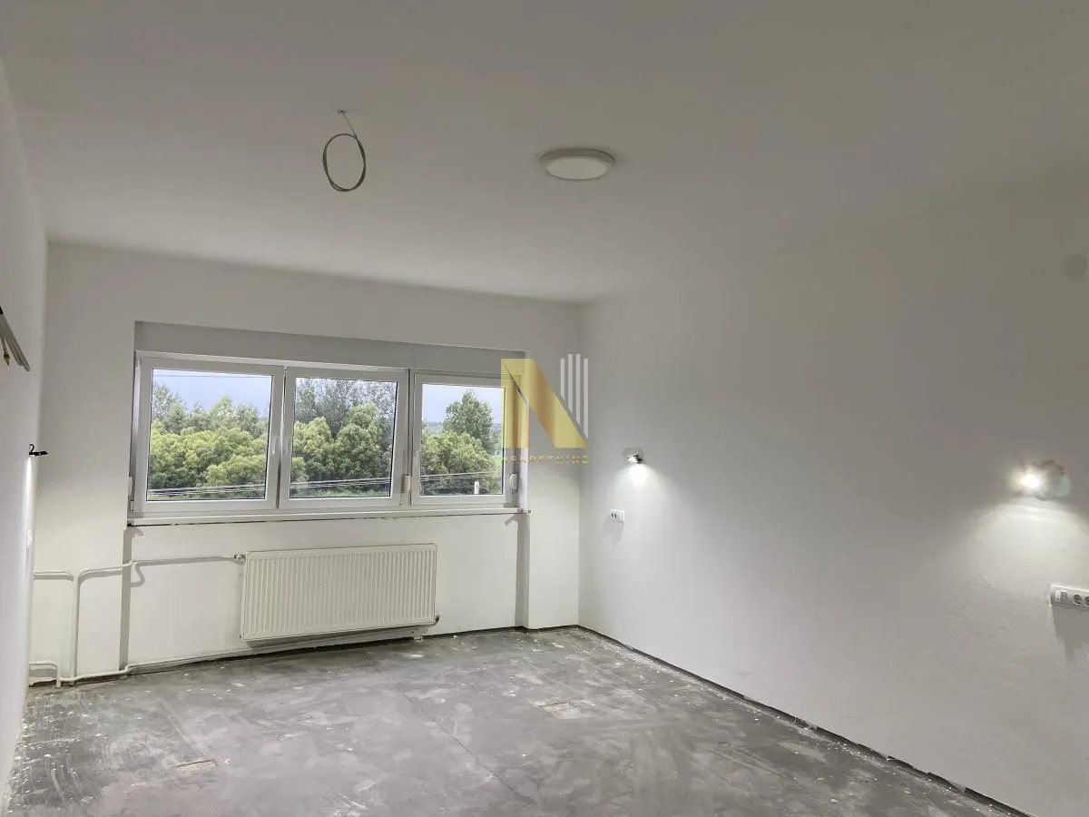 Empty unfinished room with white walls and a window.