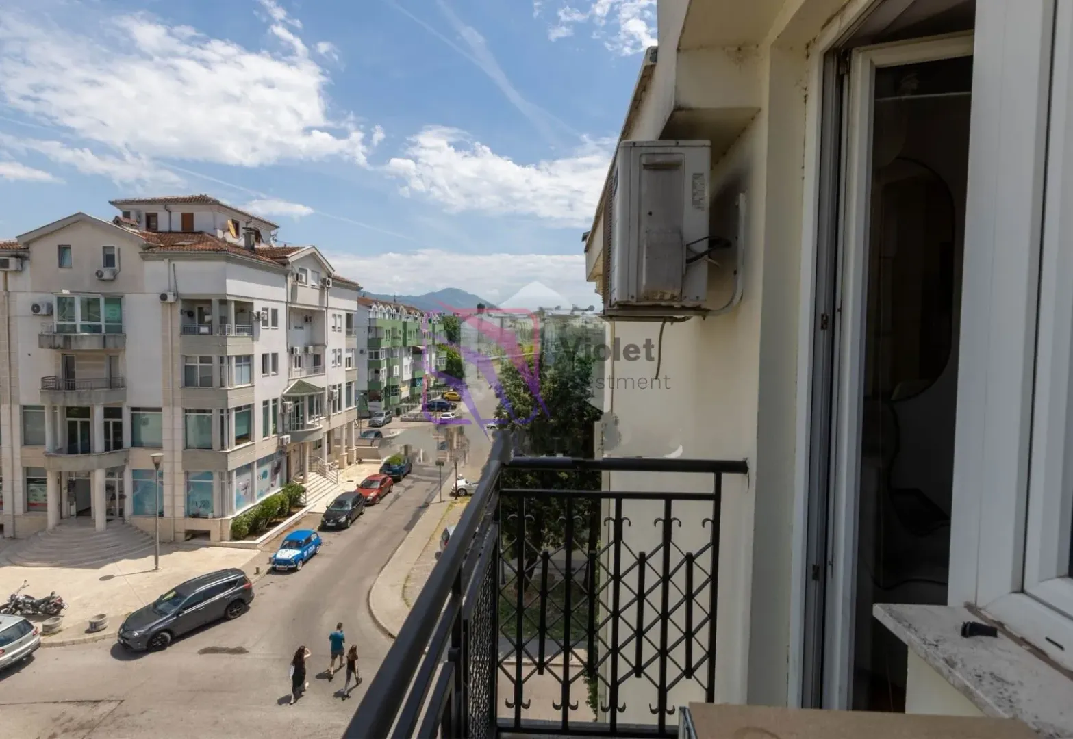 Pogled sa balkona na gradsku ulicu i okolne zgrade.