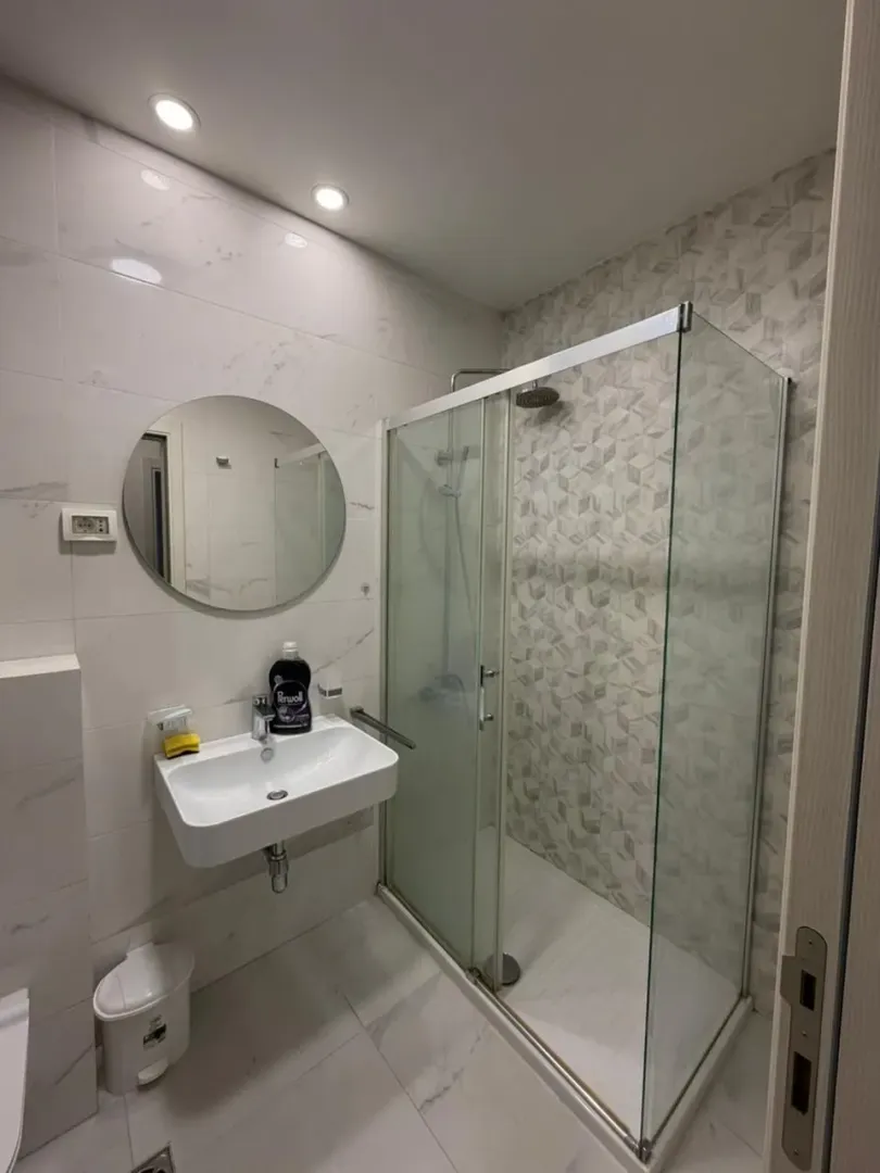 Moderne kupatilo sa umivaonikom, ogledalom i tuš kabinom.