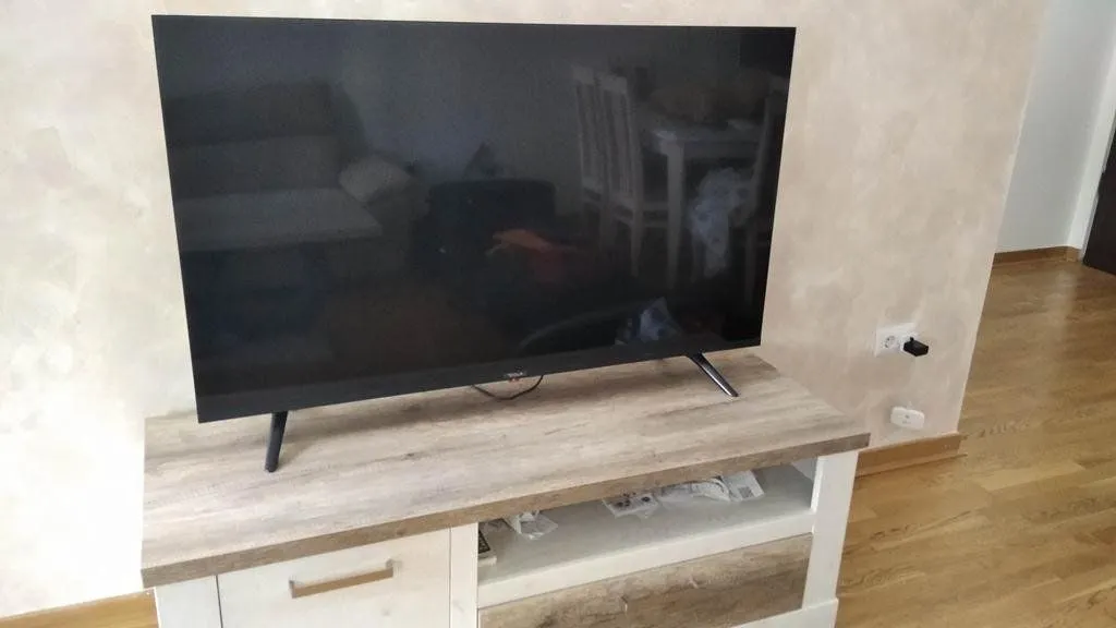 Television on a wooden chest of drawers in a room with parquet flooring.