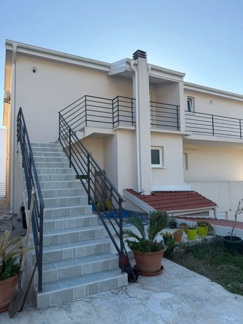 Eksterijer kuće sa spoljnim stepeništem i terasom.