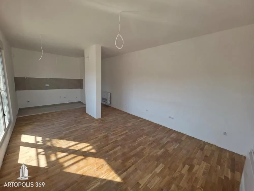 Empty room with wooden flooring and white walls.
