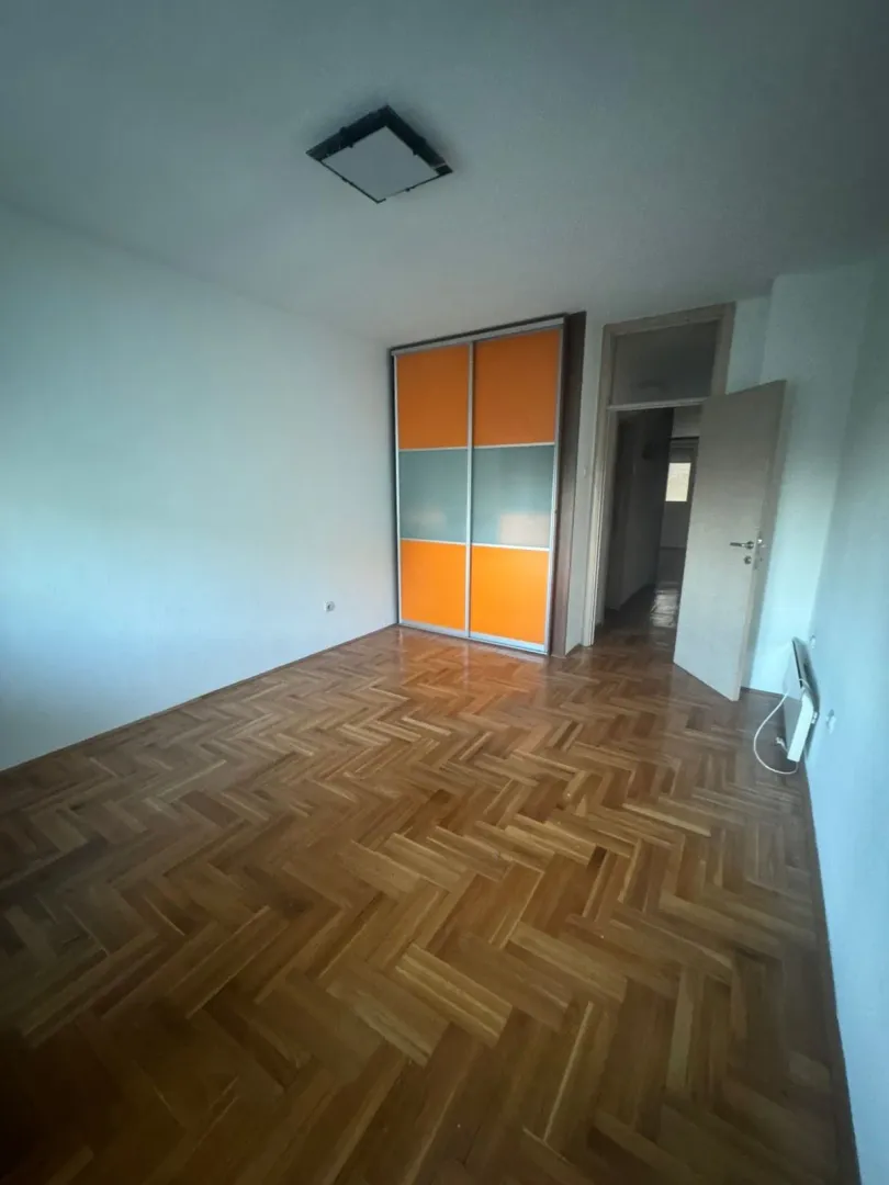 Prazna soba sa parketom i ugradnim ormarom.
