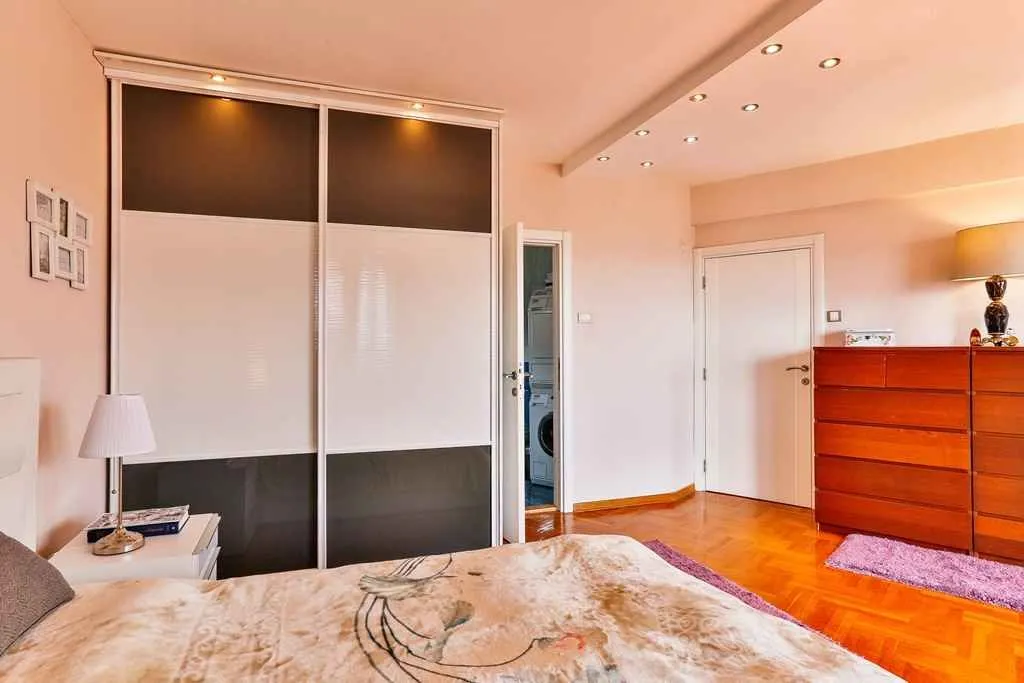 Bright bedroom featuring a large built-in wardrobe and a wooden dresser.