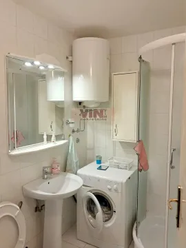 Small bathroom with a sink, shower cabin, water heater, and washing machine. - image 11