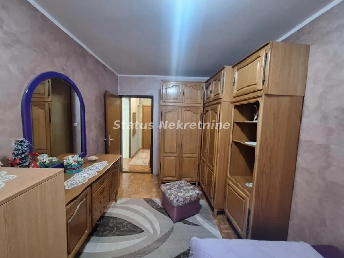 Nameštena spavaća soba sa drvenim garderoberima i komodom sa ogledalom.