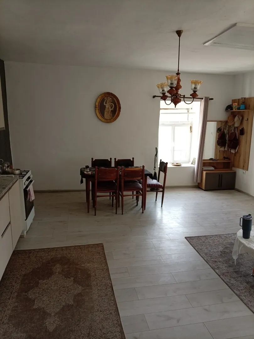 Kuhinja i trpezarija u otvorenom prostoru sa drvenim stolom i stolicama.