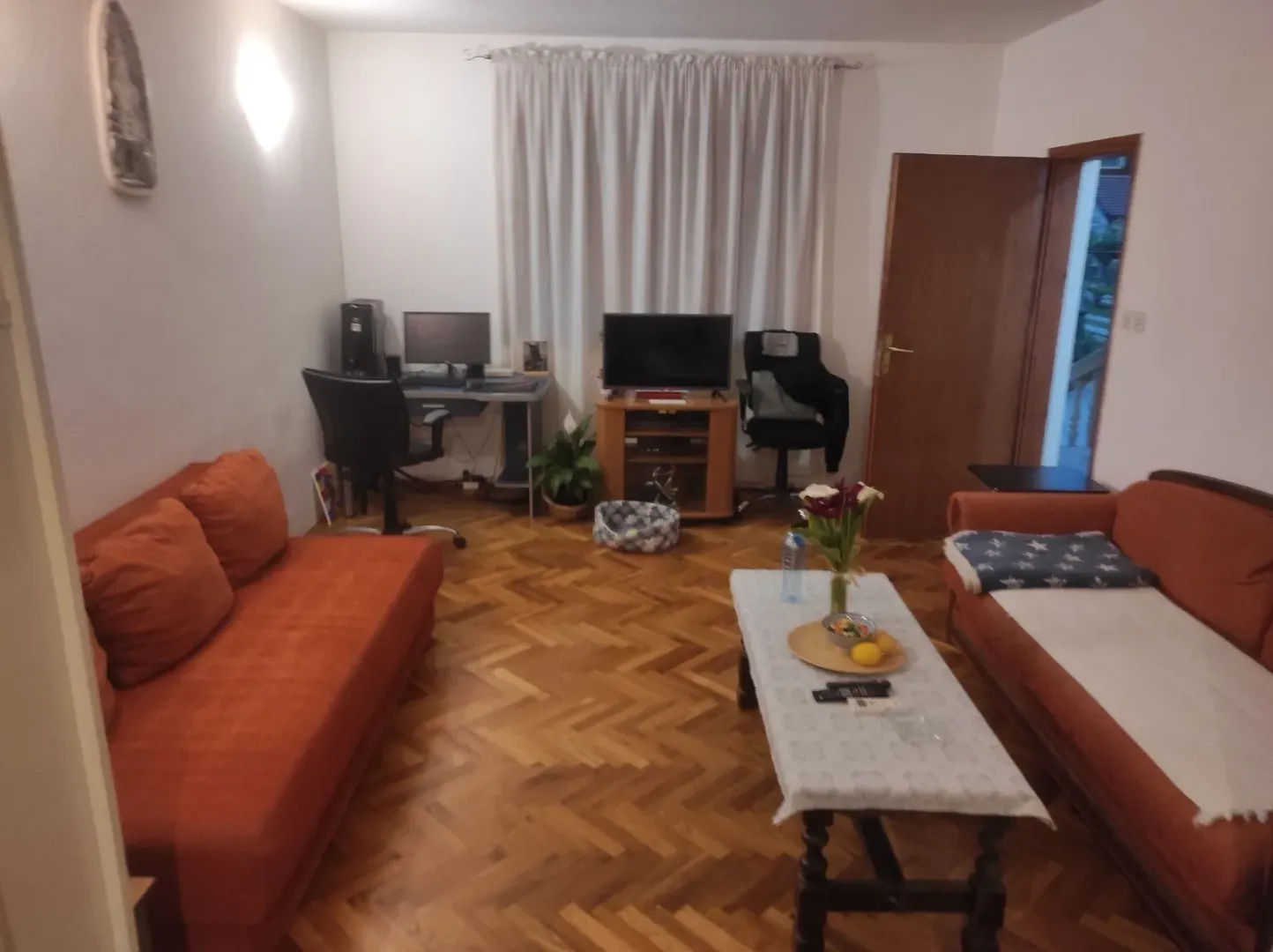 A living room featuring orange sofas and a work desk.