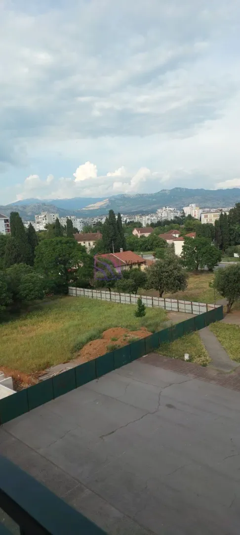 Pogled na grad, zelenilo i planine u daljini sa nekretnine.