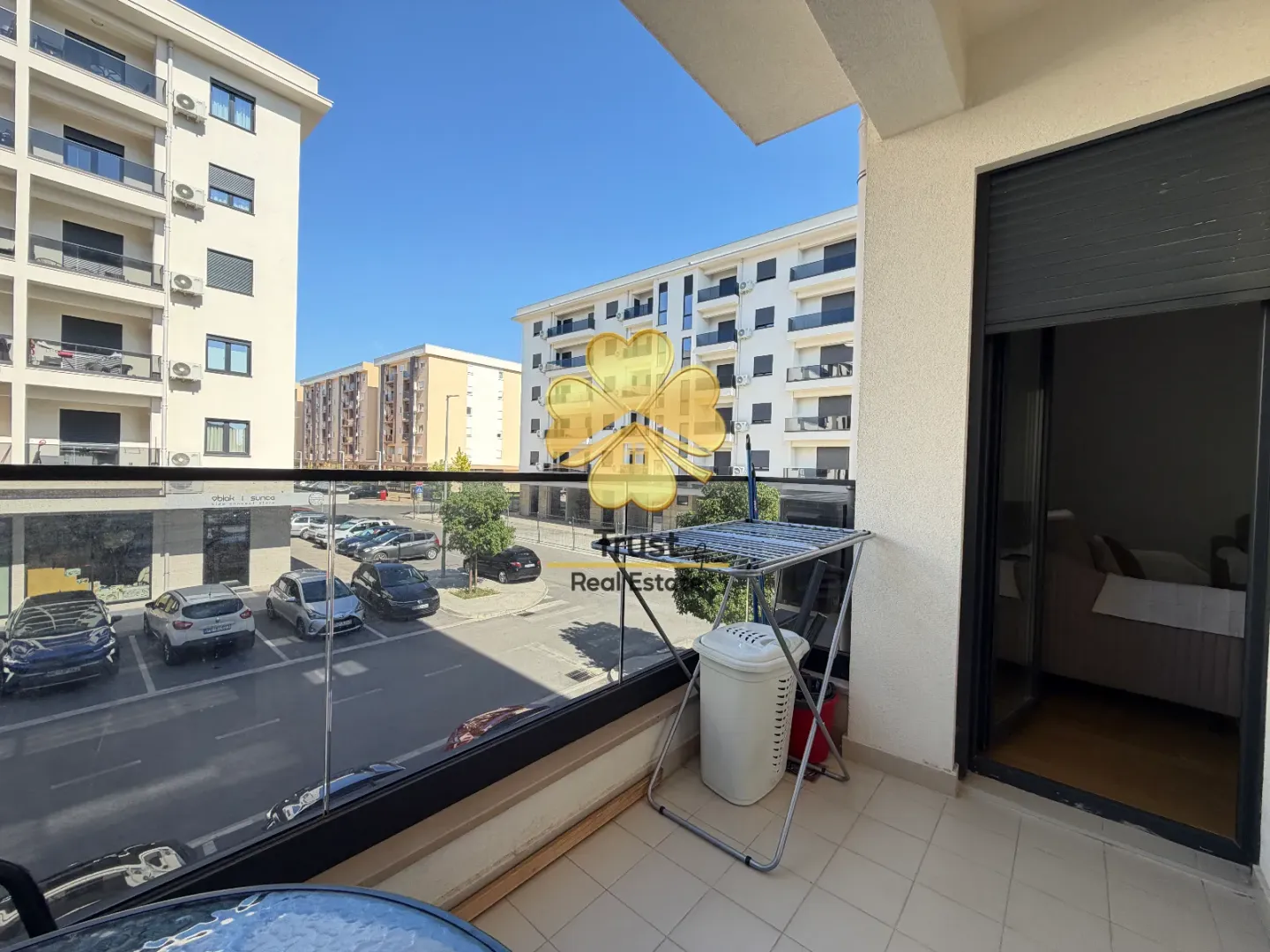 Balcony with a drying rack and a view of the parking lot and surrounding buildings.