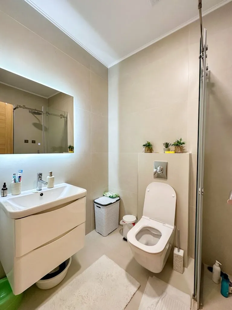 Moderno opremljeno kupatilo sa umivaonikom, WC šoljom i tuš kabinom.