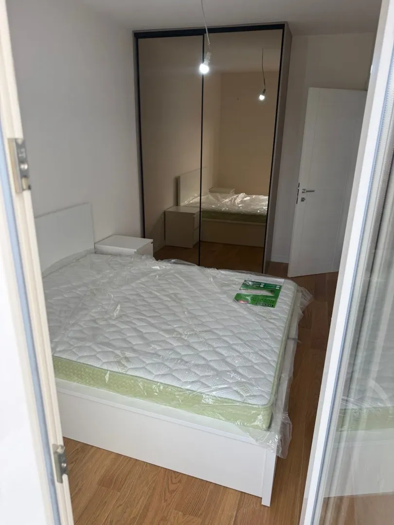 Furnished bedroom with a double bed and a large fitted wardrobe.