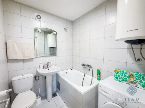 Smaller bathroom with a bathtub, washbasin, toilet, and washing machine. - image 3