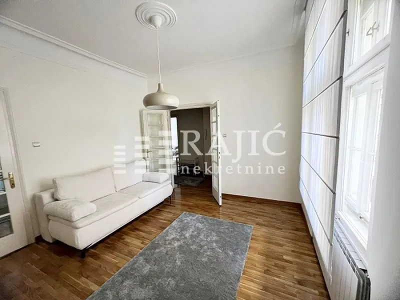 Living room with a white sofa, hardwood flooring, and a large window.