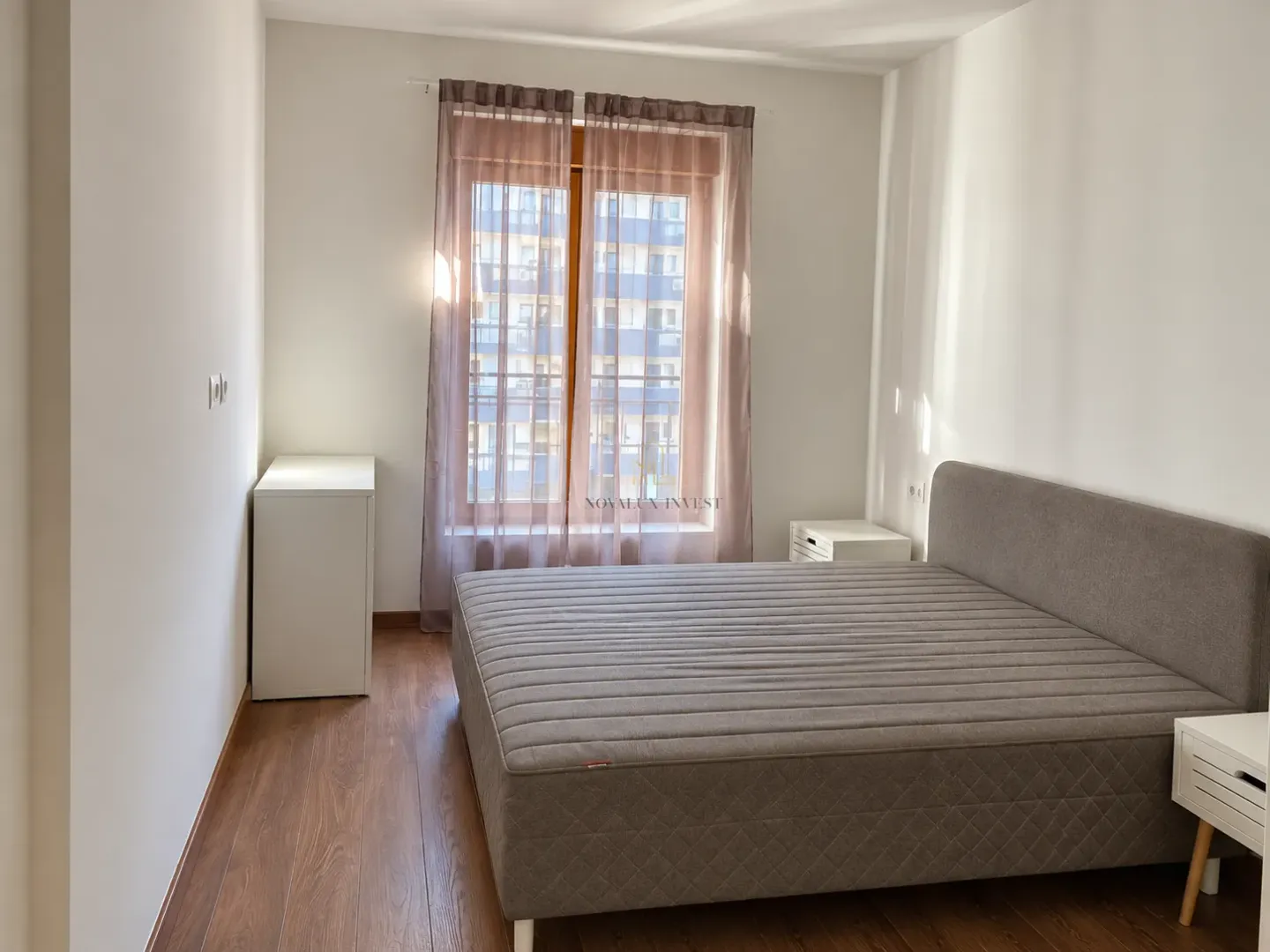 Namještena spavaća soba sa bračnim krevetom, noćnim stočićima i prozorom.
