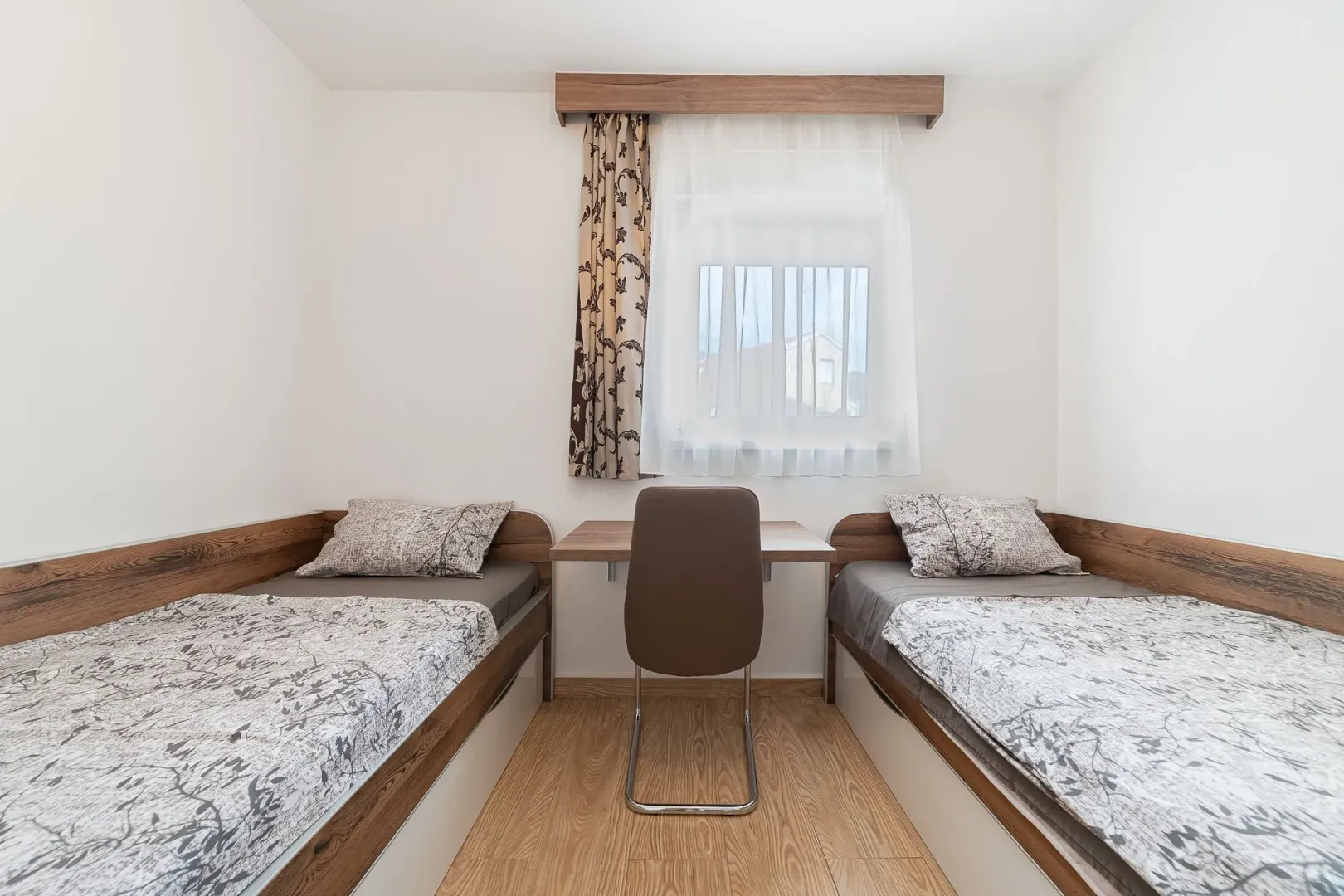 Bedroom with two single beds and a desk beneath the window.
