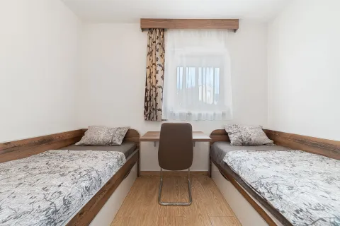 Bedroom with two single beds and a desk beneath the window. - image 2
