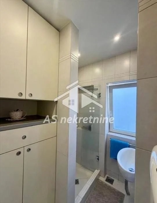 Bathroom with a shower cabin, built-in cabinet, and a window.