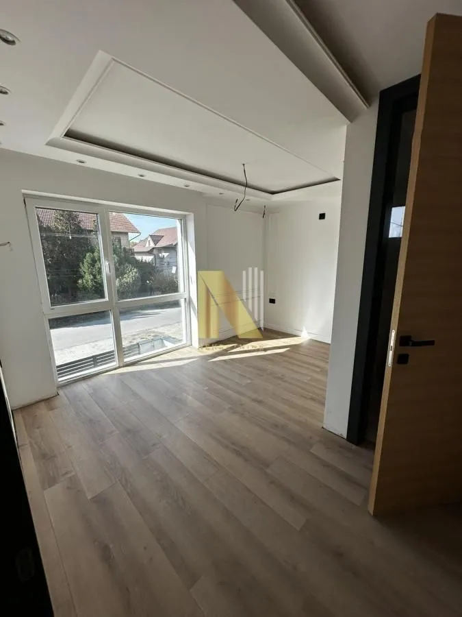 Empty room with laminate flooring, drop ceiling, and large window.