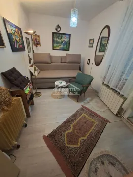 Manja dnevna soba sa garniturom za sedenje i umetničkim slikama na zidu. - image 3